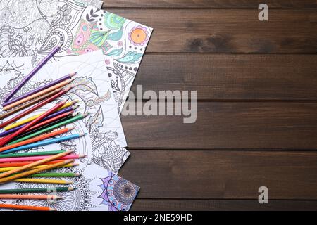 Pages de coloriage antistress et crayons sur table en bois, plat. Espace pour le texte Banque D'Images