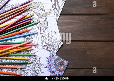 Pages de coloriage antistress et crayons sur table en bois, plat. Espace pour le texte Banque D'Images