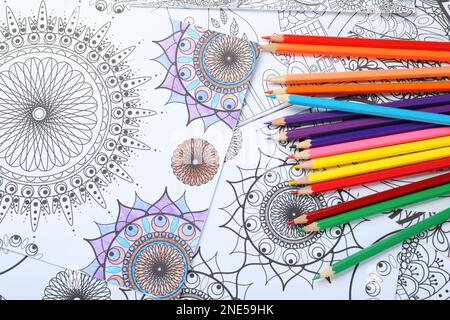 Crayons sur les pages de coloriage antistress, vue de dessus Banque D'Images