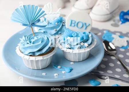 Délicieux cupcakes à la crème bleu clair et des dessus pour la douche de bébé sur la table Banque D'Images