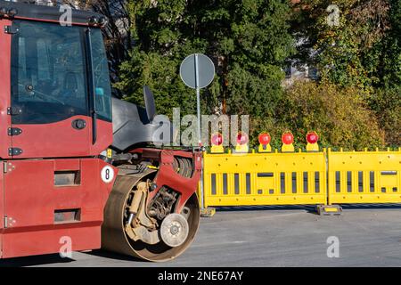 Construction de rouleau routier sur la chaussée. Barrières de sécurité jaunes avec feux de signalisation rouges. Banque D'Images