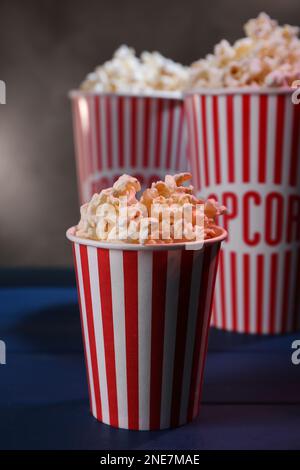 Délicieux pop-corn dans des gobelets en papier sur une table en bois bleu Banque D'Images