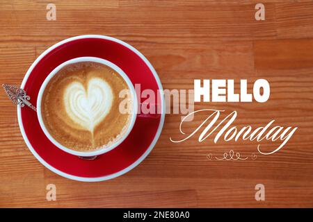 Tasse de café aromatique chaud et phrase Bonjour lundi sur fond de bois, vue de dessus Banque D'Images