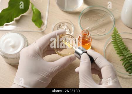 Scientifique faisant des produits cosmétiques à une table en bois, au-dessus de la vue Banque D'Images