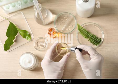 Scientifique en train de fabriquer des produits cosmétiques à la table, vue de dessus Banque D'Images