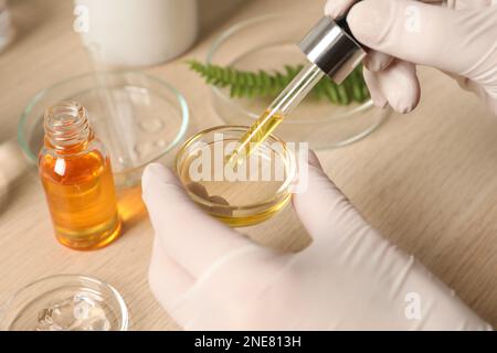 Scientifique faisant des produits cosmétiques à table en bois, gros plan Banque D'Images