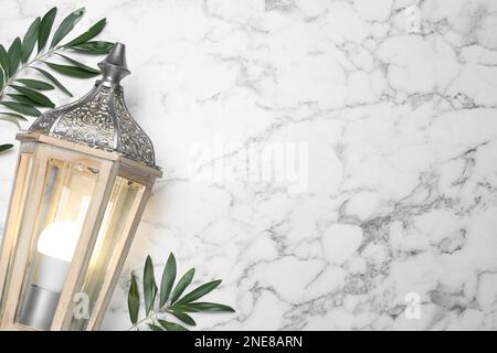 Lanterne arabe et branches vertes sur fond de marbre blanc, pose plate. Espace pour le texte Banque D'Images