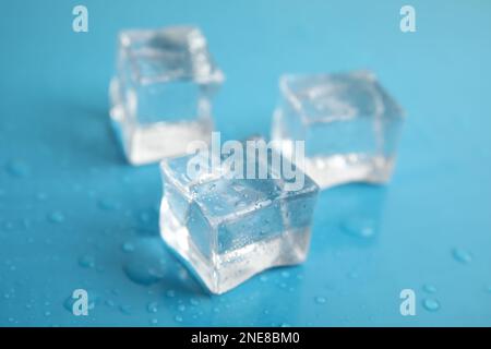 Glaçons avec gouttes d'eau sur fond bleu clair, gros plan Banque D'Images