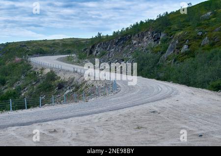 Route sinueuse dans une zone montagneuse sous un ciel nuageux d'été Banque D'Images