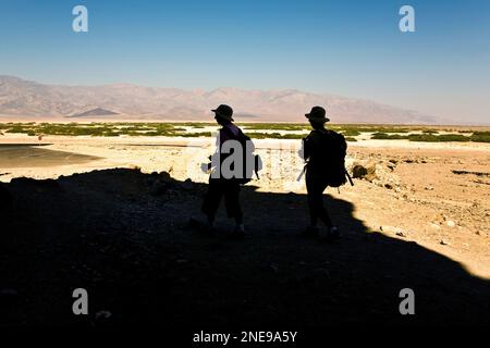 Vallée de la mort, États-Unis - 19 juillet 2008 : silhouette de deux trackers qui reviennent d'une piste dans le canyon en mosaïque de la vallée de la mort. Banque D'Images