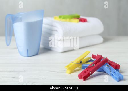 Des épingles colorées près du détergent et des serviettes sur une table en bois blanc Banque D'Images