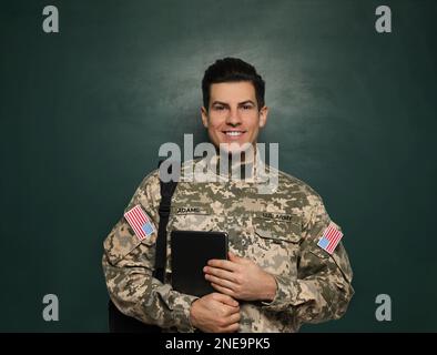 Cadet avec sac à dos et tablette près du tableau noir. Éducation militaire Banque D'Images