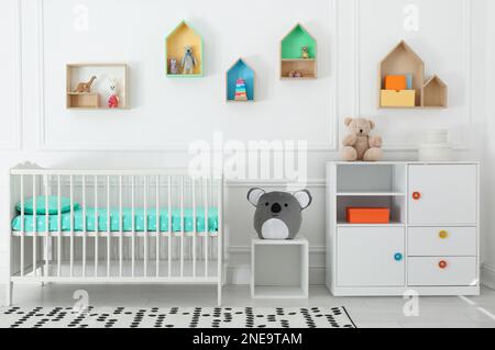 Lit de bébé confortable près du mur avec étagères colorées dans la chambre de bébé. Design intérieur Banque D'Images