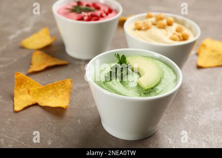 Bol de délicieux houmous verts avec avocat et persil sur une table en marbre brun Banque D'Images