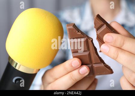 Femme faisant des sons ASMR avec microphone et chocolat, gros plan Banque D'Images