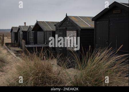Cabanes de plage noires à Walberswick, Suffolk. Gris, moody. Banque D'Images