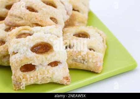 Gros plan de strudel aux pommes fraîches et cuites au four, de délicieuses petites morsures, sur une assiette carrée vert clair sur fond blanc Banque D'Images