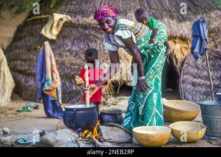 Niger - une femme avec ses enfants cuisant le dîner. Banque D'Images