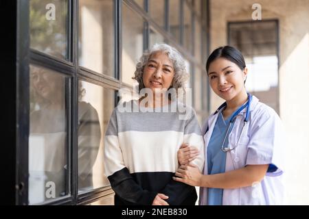 Jeune aidant une femme âgée à marcher. Infirmière aidant sa vieille patiente à la maison de soins. Femme âgée avec bâton de marche aidé par Banque D'Images