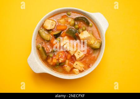 Délicieux calamar de ragoût avec des légumes dans un bol sur fond jaune Banque D'Images