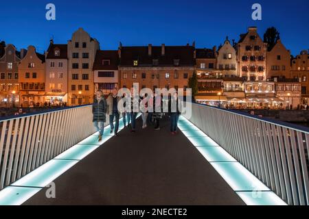 Horizon nocturne dans la ville de Gdańsk en Pologne, les gens sur la passerelle de l'Esprit Saint au-dessus de la rivière Motława dans la vieille ville. Banque D'Images