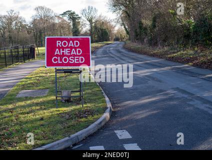 27 janvier 2022 - un panneau rouge avec inscription blanche indiquant la route en avant fermé sur les jambes avec un poids de sac de sable. Banque D'Images