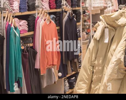 Une collection colorée de vêtements d'automne et d'hiver pour femmes est suspendue sur un cintre dans le magasin. Banque D'Images