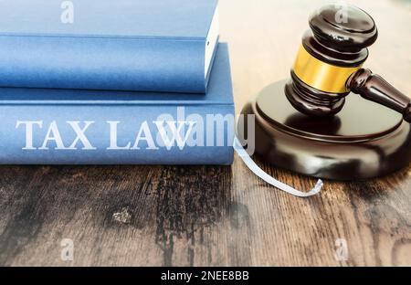 Gros plan du juge Gavel et livre avec texte DE LOI FISCALE sur table rustique en bois Banque D'Images