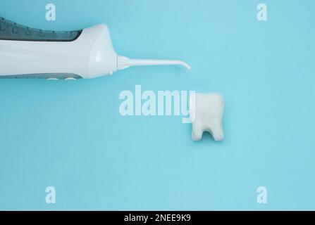 Irrigateur avec silhouette de modèle de dent sur fond bleu, dents propres professionnelles, les dents seront bonnes santé. Concept de soins dentaires et oraux. De Banque D'Images