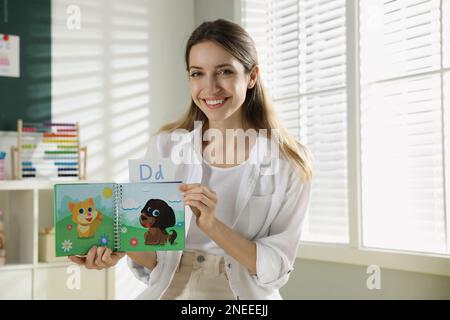 Bonne enseignante d'anglais féminine donnant la leçon à l'école primaire Banque D'Images