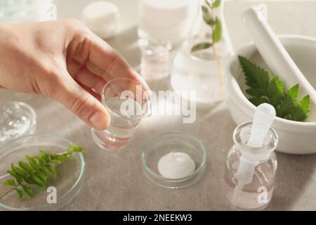 Scientifique faisant des produits cosmétiques à la table grise, gros plan Banque D'Images