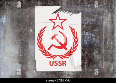 Mur en béton recouvert d'un mur plein cadre avec une affiche déchirée au milieu représentant en rouge, le symbole de l'URSS communiste Laurel Hammer Sickle avec 'URSS Banque D'Images