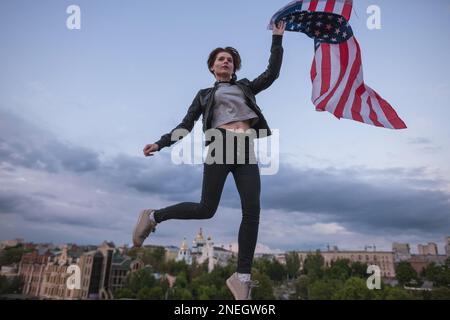 Fille qui saute avec drapeau volant américain Banque D'Images