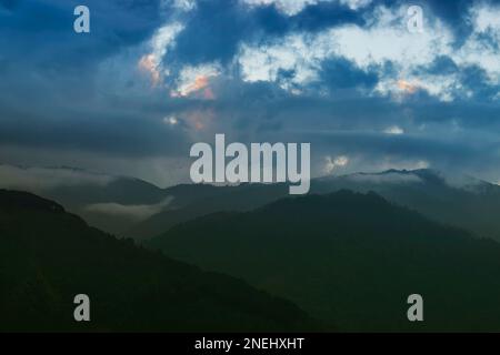 Des nuages colorés au-dessus de la chaîne de montagnes de l'Himalaya après que le soleil s'est installé au-delà des sommets de montagne. Après le coucher du soleil image de stock nature , tourné à Okhrey, Sikkim Banque D'Images