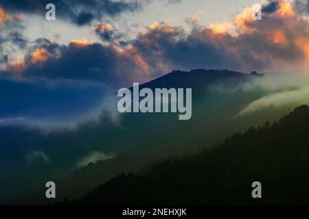 Des nuages colorés au-dessus de la chaîne de montagnes de l'Himalaya après que le soleil s'est installé au-delà des sommets de montagne. Après le coucher du soleil image de stock nature , tourné à Okhrey, Sikkim Banque D'Images