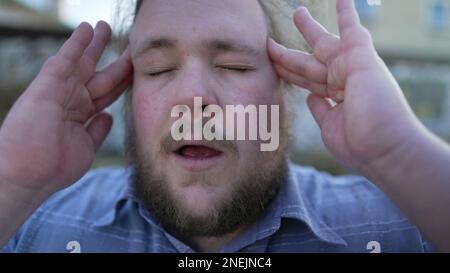 Portrait de la personne souffrant de migraine appuyant les doigts aux temples fermer les yeux avec l'expression du visage sans défense. Un jeune homme de corbeaux ayant la tête Banque D'Images