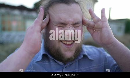 Portrait de la personne souffrant de migraine appuyant les doigts aux temples fermer les yeux avec l'expression du visage sans défense. Un jeune homme de corbeaux ayant la tête Banque D'Images