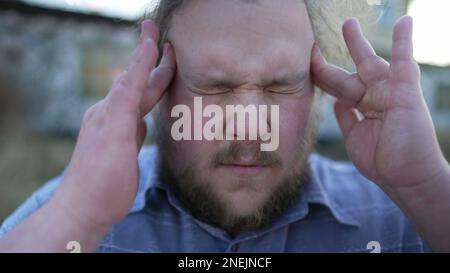 Portrait de la personne souffrant de migraine appuyant les doigts aux temples fermer les yeux avec l'expression du visage sans défense. Un jeune homme de corbeaux ayant la tête Banque D'Images