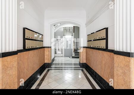 Long hall sur les murs avec des boîtes aux lettres en marbre orange des deux côtés pour la correspondance et les lettres. Au bout de la salle il y a un moderne Banque D'Images