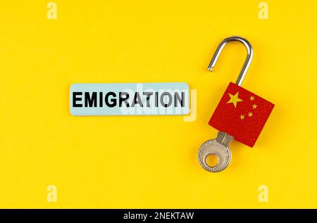 Sur une surface jaune, une serrure ouverte avec l'image du drapeau de la Chine et un autocollant avec l'inscription - émigration Banque D'Images