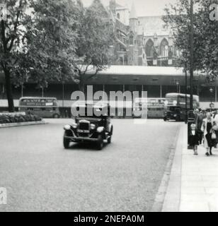 Londres, Angleterre. 1953. Vue de la place du Parlement des stands temporaires érigés à l'extérieur de l'abbaye de Westminster, en particulier pour le couronnement de la reine Elizabeth II, qui a eu lieu le 2nd juin 1953. Les bus londoniens passent et un taxi londonien 1930s d'Austin est au premier plan. Banque D'Images