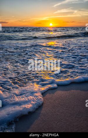 Vue à angle bas au niveau du sol vue rapprochée du coucher de soleil vertical coloré sur la côte du golfe du Mexique avec vague d'eau dans la plage de Seaside Santa Rosa, en Floride Panhandle Banque D'Images