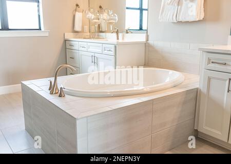 Salle de bains intérieure dans un nouvel appartement de luxe moderne avec nouvelle grande baignoire avec robinet par fenêtre lumineuse et personne Banque D'Images