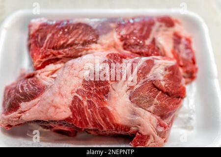 Viande de porc ou de boeuf de côtes courtes graisse de viande sur plateau plastique blanc contenant macro gros plan avec texture de détail de la boucherie d'épicerie Banque D'Images