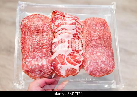 Tranches de salami avec sopressata non guéri, coppa et salami de gênes sans nitrites sur plateau en plastique avec viande de porc rouge Banque D'Images