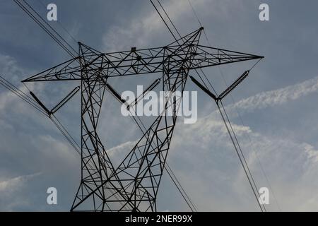 Gros plan à faible angle de la tour de transmission d'électricité dans un quartier résidentiel, dans un ciel bleu partiellement nuageux. Banque D'Images