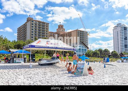 Naples, Etats-Unis - 28 décembre 2021: Plage Vanderbilt en Floride au sud-ouest avec hôtel Ritz-Carlton et panneau pour les locations de bateaux WaveRunner et Banana Boat ri Banque D'Images