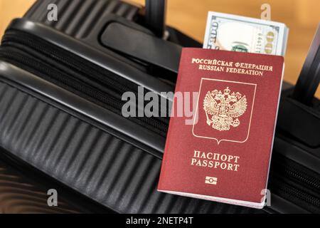 Concept de départ de voyage sous la forme d'un passeport avec des dollars américains joints sur une valise noire Banque D'Images