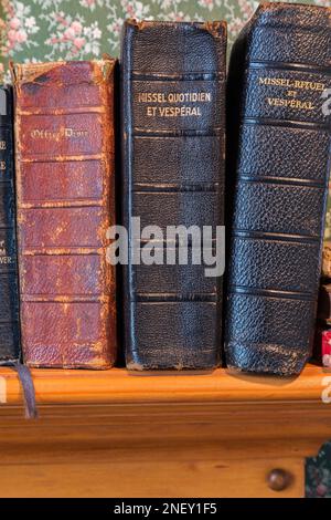 Gros plan de vieux livres liturgiques rouges et noirs liés en cuir sur une étagère dans la chambre d'hôtes à l'étage à l'intérieur de la vieille maison américaine de 1927 places. Banque D'Images