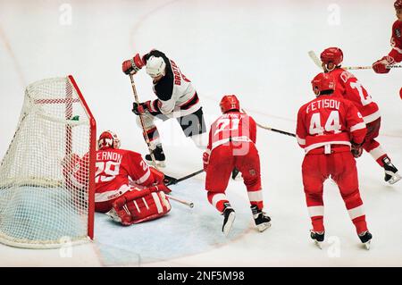 Detroit Red Wings goalie Mike Vernon, right, tries and fails to stop the  puck after it deflected off the skate of New Jersey Devils center Neal  Broten (9) for the score in
